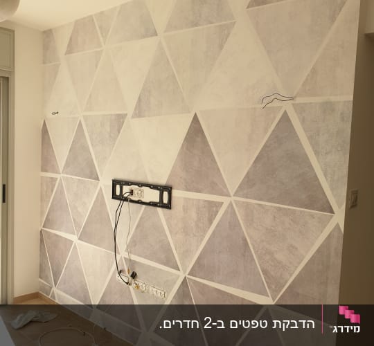 קיר מעוצב בטפט גיאומטרי בדוגמת משולשים בגווני אפור ובז